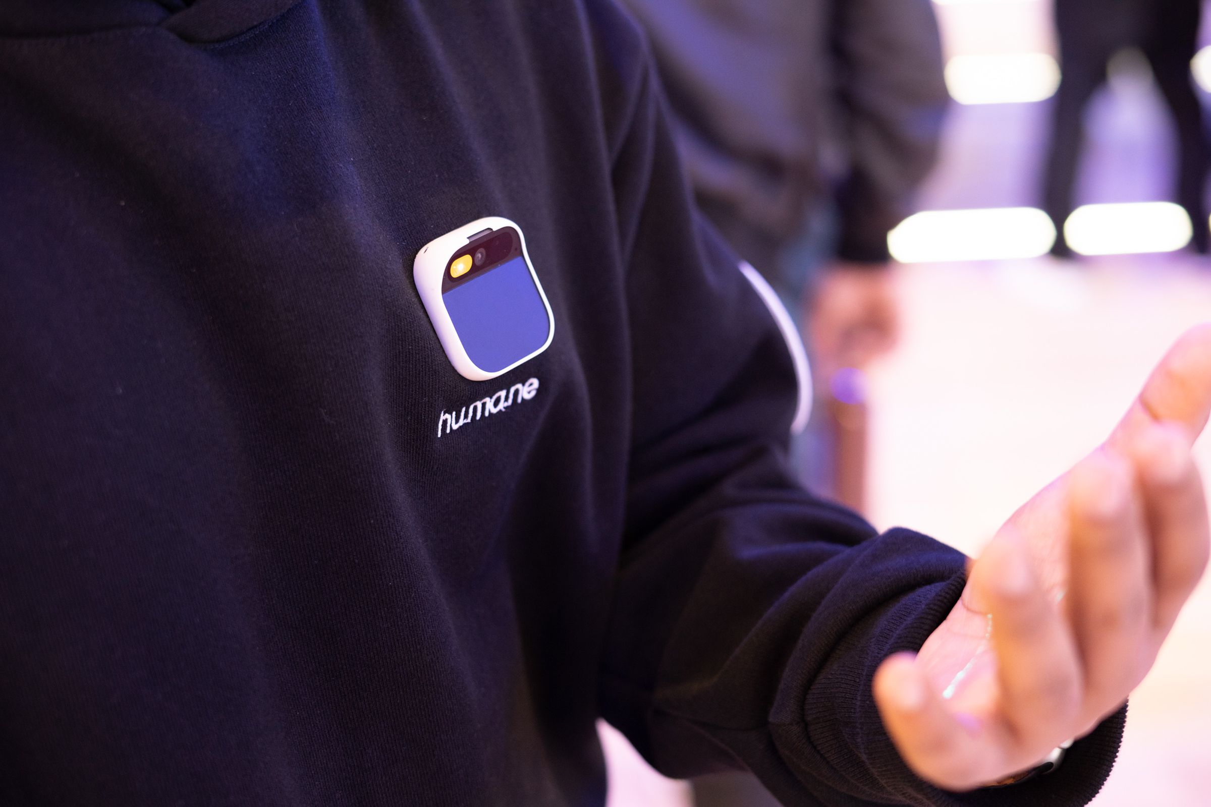 Humane AI pin on a shirt projecting text onto a person's hand.