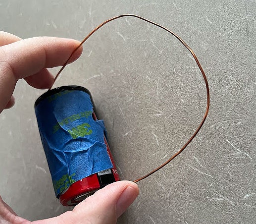 A battery with⁣ copper wire attached⁤ to both ends and ⁢a piece of blue tape over its surface