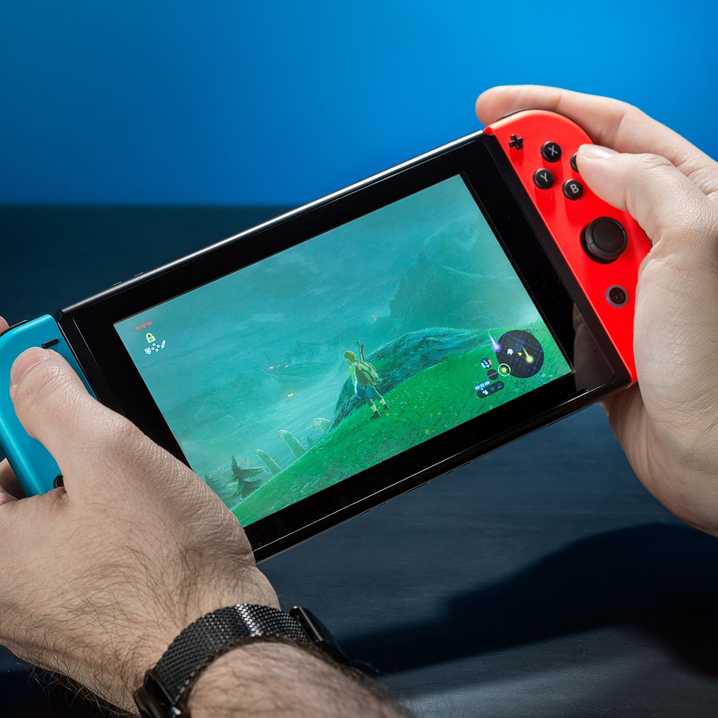 A person enjoying The Legend of Zelda: Breath of the Wild on a Nintendo Switch handheld device.