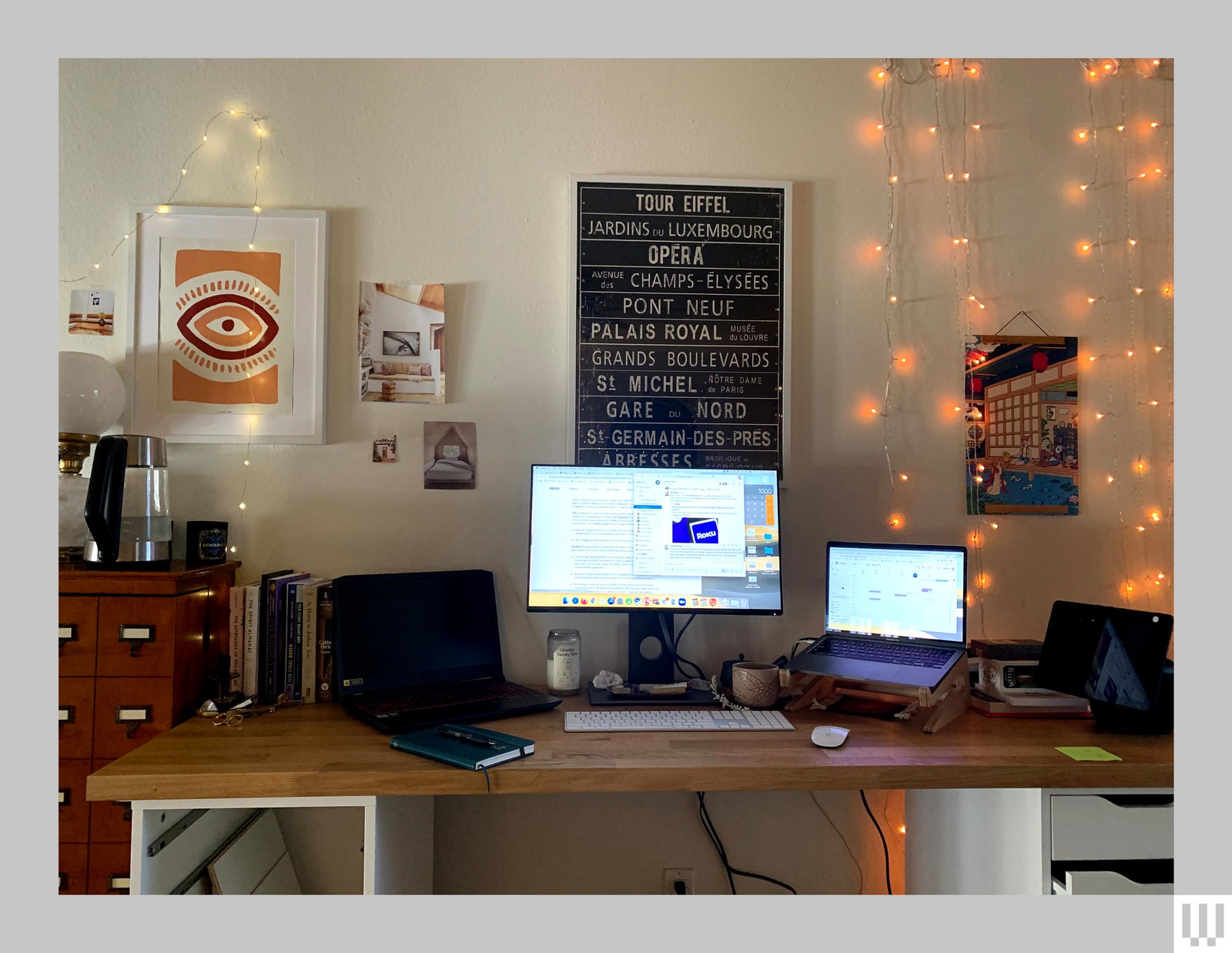 Home desk ​with a⁤ computer monitor two⁣ laptops a computer ⁢keyboard and mouse in front of a white ‌wall with artwork and...