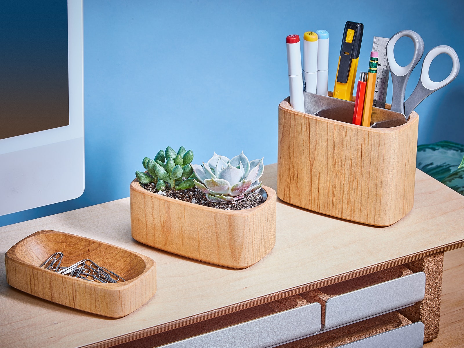 Simple two ⁤tier wooden ⁣shelf with a computer monitor on top and 3 wooden containers holding paperclips scissors and...